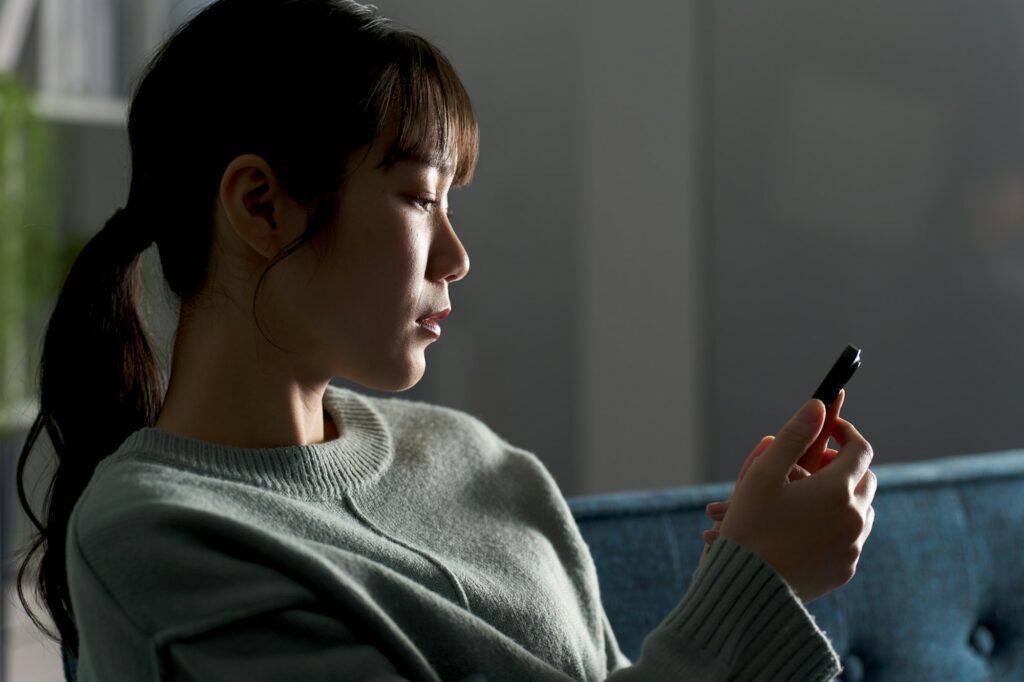 A depressed woman looking at her smartphone